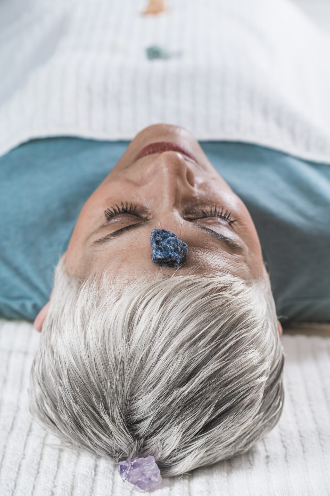 Chakra Healing Treatment Healing and Balancing Chakras Therapy. Beautiful elderly woman lying on massage table and enjoying chakra healing treatment